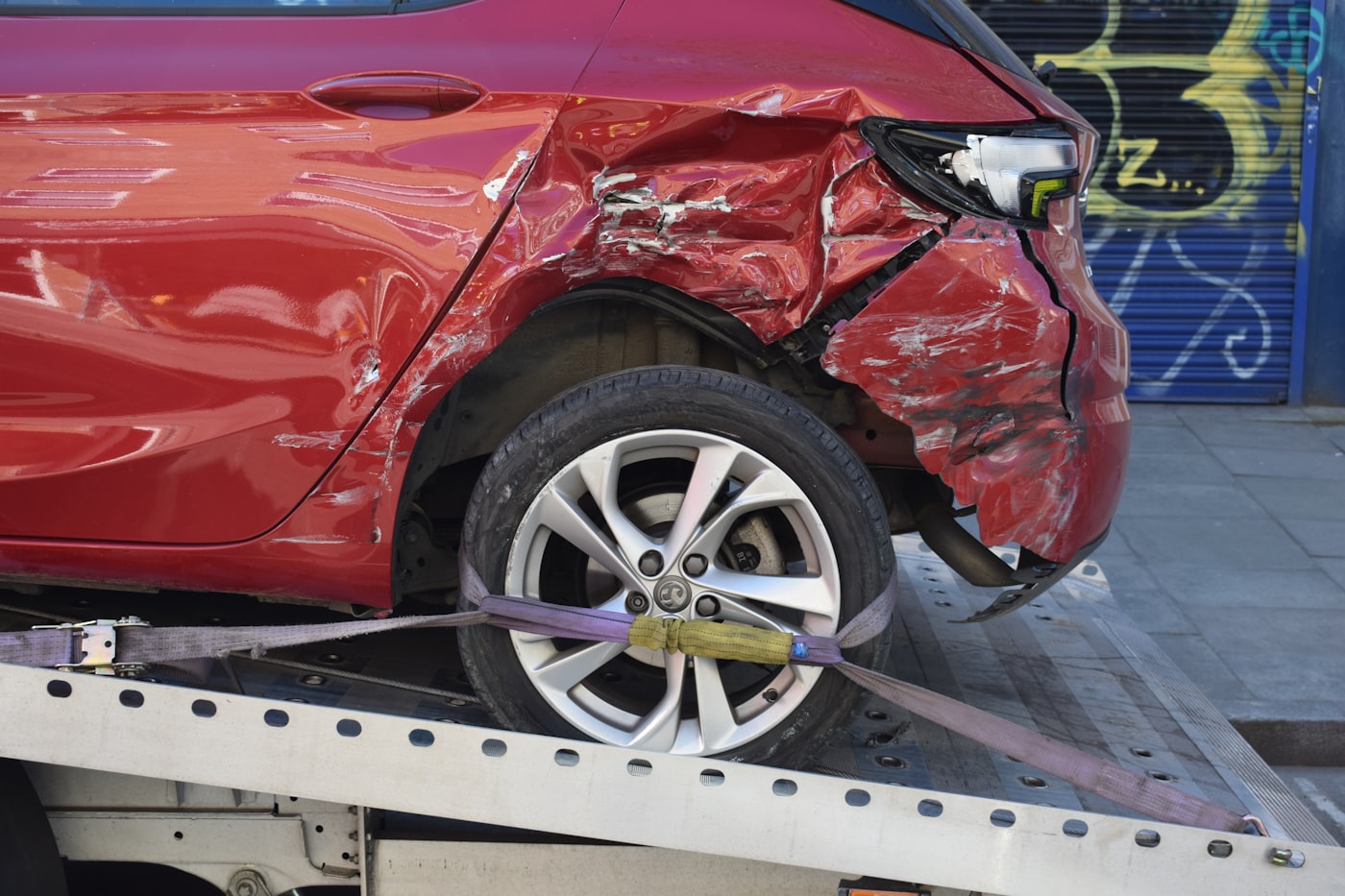 A car with rear collision damage on a tow truck flatbed